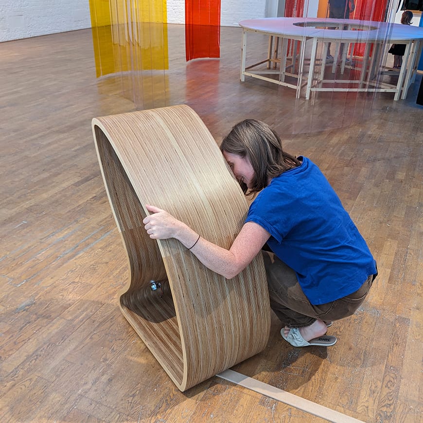Adult female squatting down hugging wooden sculpture