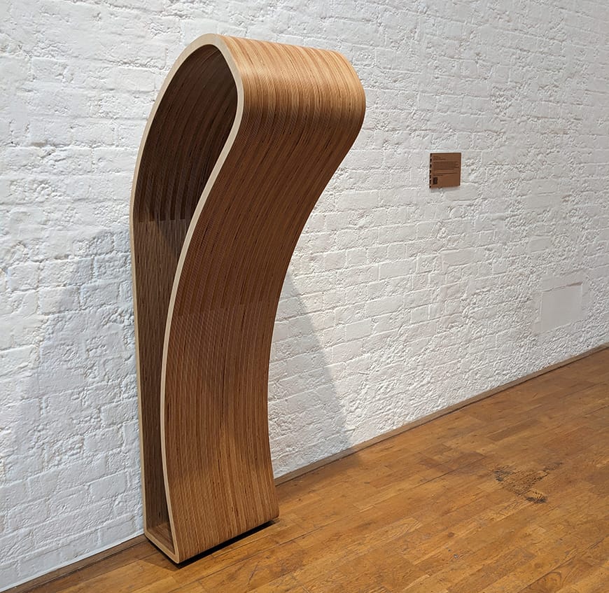 A life-sized wooden sculpture in the shape of a simple body form