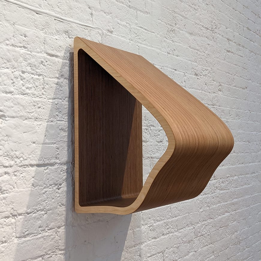 A wall-mounted wooden sculpture on a white wall