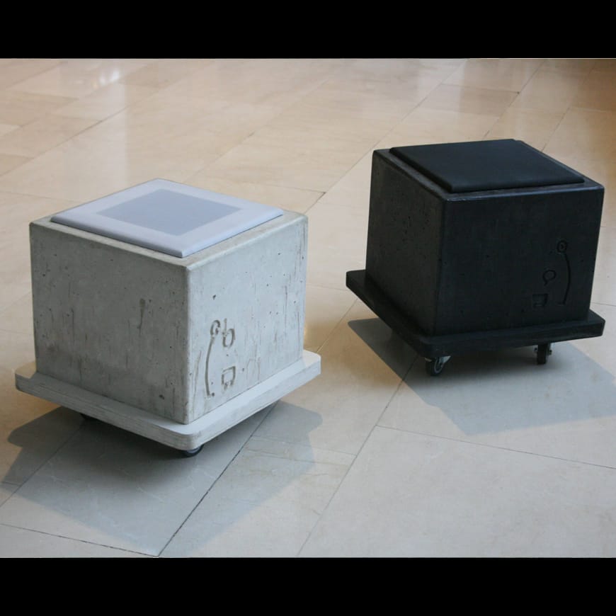 Two concrete cubes on castors, one grey, one black