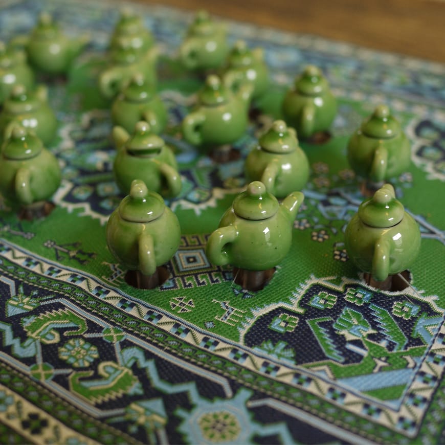 A series of miniature green teapots seen close up