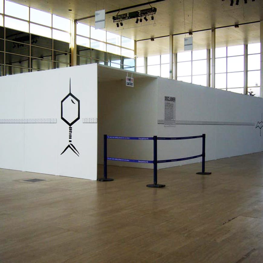 Photograph of white exhibition structure with Disclaimer sign by doorway
